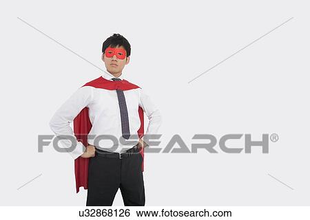 Stock Photograph - Confident Asian businessman in superhero costume. Fotosearch