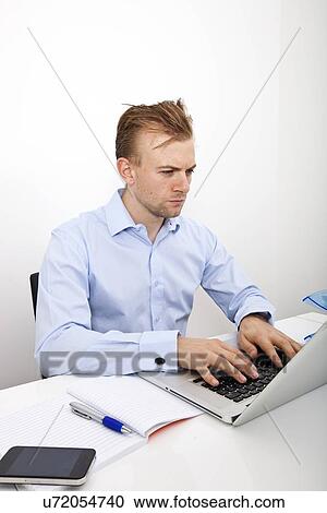 Confident businessman using laptop at desk in office View Large Photo Image Stock Image - Confident businessman using laptop at desk in office. Fotosearch