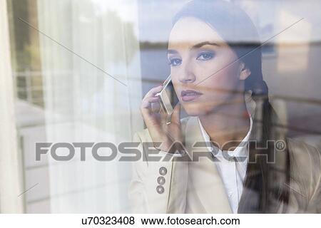Confident businesswoman using cell phone in office View Large Photo Image Stock Photo - Confident businesswoman using cell phone in office. Fotosearch