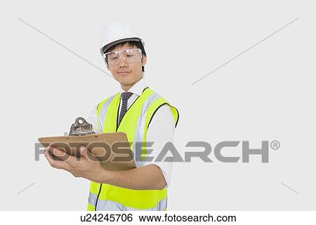 Confident construction worker holding clipboard in office View Large Photo Image Stock Photograph - Confident construction worker holding clipboard in office. Fotosearch