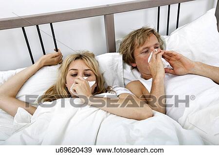 Couple suffering from cold lying on bed View Large Photo Image Stock Photo - Couple suffering from cold lying on bed. Fotosearch