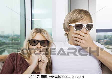 Couple wearing 3D glasses and watching TV with concentration at home View Large Photo Image Stock Photo - Couple wearing 3D glasses and watching TV with concentration at home. Fotosearch