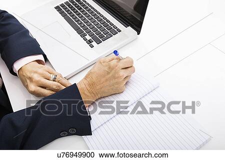 Cropped image of businesswoman with laptop writing in notebook on office desk View Large Photo Image Stock Image - Cropped image of businesswoman with laptop writing in notebook on office desk. Fotosearch