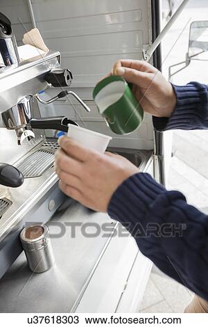 Stock Image - Cropped image of man pouring milk in cup at mobile coffee shop. Fotosearch