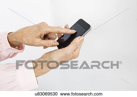 Stock Image - Cropped image of senior businesswoman using smart phone in office. Fotosearch