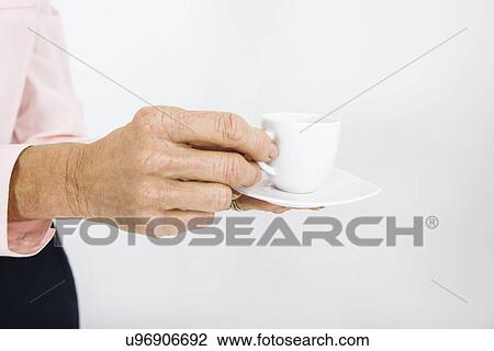 Stock Image - Cropped image of senior businesswoman with espresso cup at office. Fotosearch