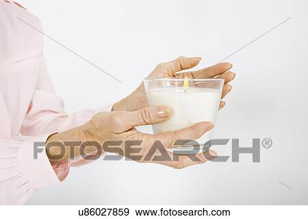Stock Photo - Cropped image of senior businesswoman holding lit candle in office. Fotosearch