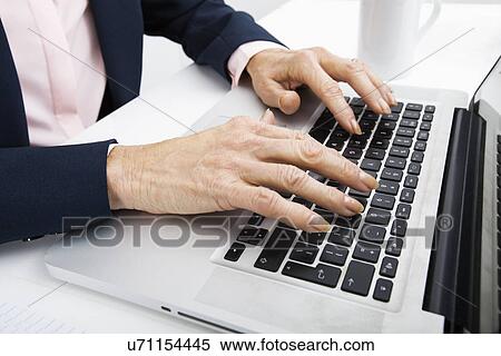 Stock Photography - Cropped image of senior businesswoman typing on laptop. Fotosearch