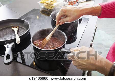 Stock Image - Cropped image of senior woman preparing food at kitchen counter. Fotosearch