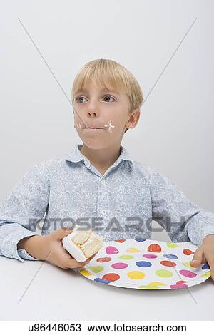 Cute boy with cake slice in plate on table looking away at home View Large Photo Image Stock Image - Cute boy with cake slice in plate on table looking away at home. Fotosearch