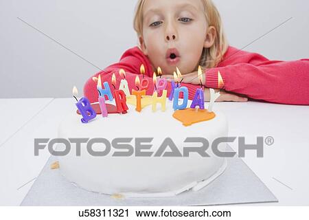 Cute girl blowing birthday candles at table in house View Large Photo Image Stock Image - Cute girl blowing birthday candles at table in house. Fotosearch
