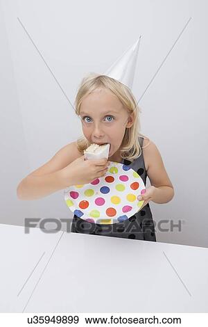 Cute girl eating birthday cake slice at table in house View Large Photo Image Stock Photo - Cute girl eating birthday cake slice at table in house. Fotosearch