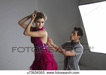 Designer adjusting dress back of fashion model in studio View Large Photo Image Stock Image - Designer adjusting dress back of fashion model in studio. Fotosearch