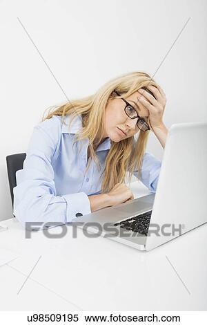 Stock Photography - Exhausted businesswoman looking at laptop in office. Fotosearch