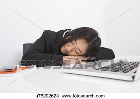 Stock Image - Exhausted businesswoman resting at office desk. Fotosearch