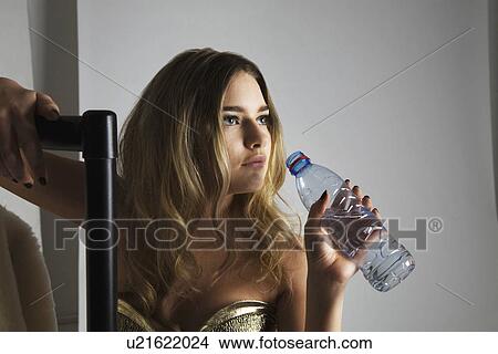 Picture - Fashion model drinking water from bottle in studio. Fotosearch
