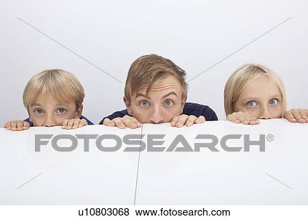 Father and children peeking over table View Large Photo Image Stock Photo - Father and children peeking over table. Fotosearch