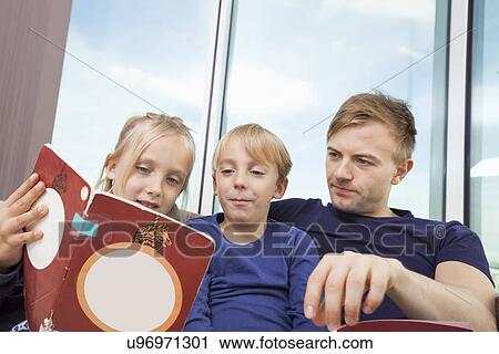 Father and children reading storybook at home View Large Photo Image Stock Image - Father and children reading storybook at home. Fotosearch