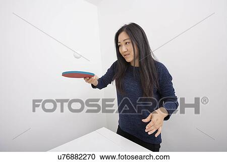 Stock Image - Female table tennis player bouncing ball on paddle. Fotosearch