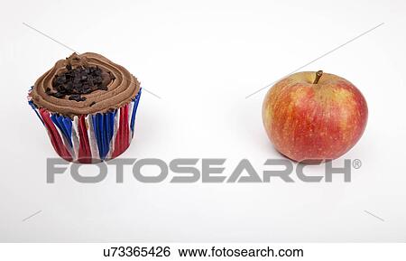 Stock Photograph - Fresh apple and chocolate cupcake against white background. Fotosearch