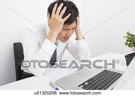 Frustrated businessman with head in hands sitting at desk in office View Large Photo Image Stock Photograph - Frustrated businessman with head in hands sitting at desk in office. Fotosearch
