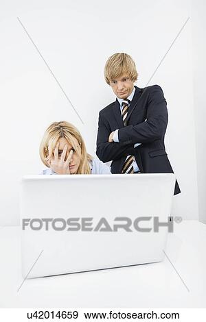 Frustrated businesspeople looking at laptop in office View Large Photo Image Stock Photo - Frustrated businesspeople looking at laptop in office. Fotosearch