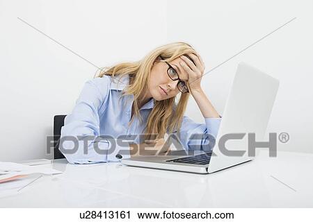 Frustrated businesswoman looking at laptop in office View Large Photo Image Stock Image - Frustrated businesswoman looking at laptop in office. Fotosearch