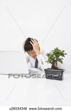 Frustrated mid adult businessman with laptop at desk in office View Large Photo Image Stock Photo - Frustrated mid adult businessman with laptop at desk in office. Fotosearch