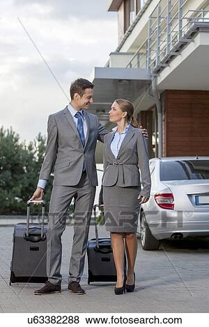 Full-length of business couple walking with luggage outside hotel View Large Photo Image Stock Photo - Full-length of business couple walking with luggage outside hotel. Fotosearch