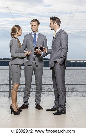 Full length of businesspeople with wineglasses standing on terrace View Large Photo Image Stock Image - Full length of businesspeople with wineglasses standing on terrace. Fotosearch