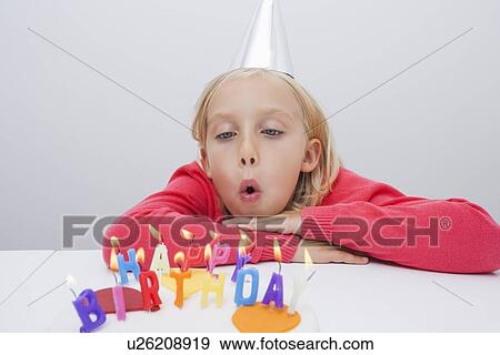 Girl blowing birthday candles at table in house View Large Photo Image Stock Photo - Girl blowing birthday candles at table in house. Fotosearch
