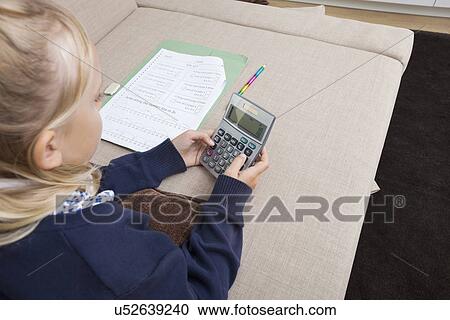 Girl using calculator while studying on sofa View Large Photo Image Stock Image - Girl using calculator while studying on sofa. Fotosearch