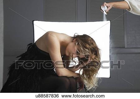 Stock Photograph - Hairstylist spraying hair product on female model's hair. Fotosearch