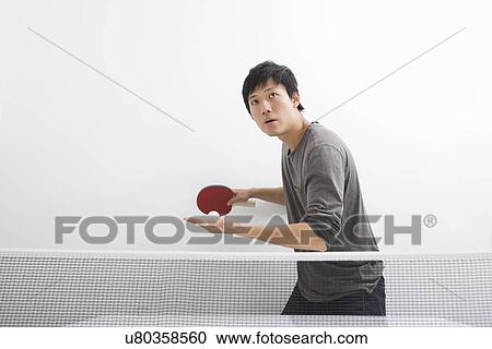 Stock Image - Handsome Asian man playing ping pong. Fotosearch