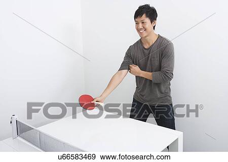 Stock Photo - Handsome mid adult man playing table tennis. Fotosearch