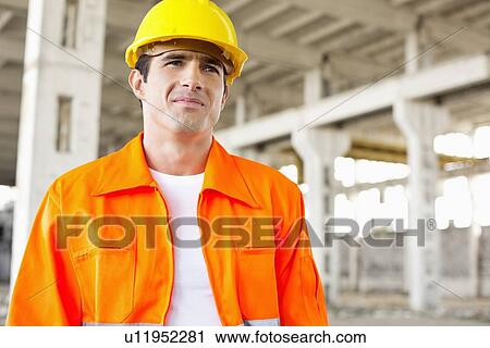 Handsome mid adult man wearing protective workwear at construction site View Large Photo Image Stock Image - Handsome mid adult man wearing protective workwear at construction site. Fotosearch