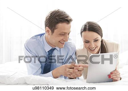 Happy business couple using digital tablet in hotel room View Large Photo Image Stock Photo - Happy business couple using digital tablet in hotel room. Fotosearch