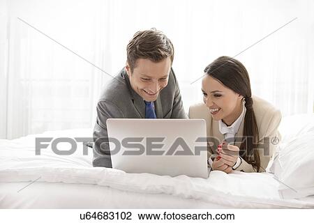 Happy business couple using laptop in hotel room View Large Photo Image Stock Image - Happy business couple using laptop in hotel room. Fotosearch