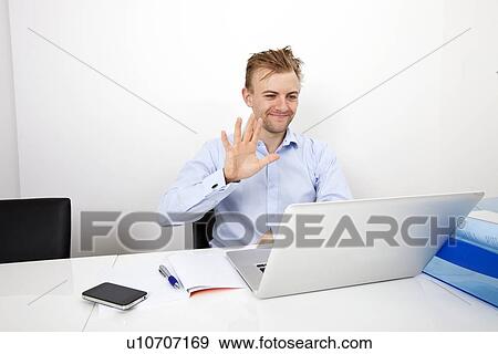 Stock Photo - Happy businessman video conferencing on laptop in office. Fotosearch