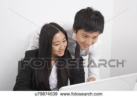 Happy businesspeople discussing over laptop in office View Large Photo Image Stock Photo - Happy businesspeople discussing over laptop in office. Fotosearch