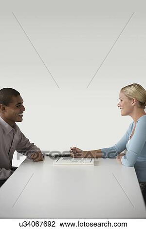 Stock Image - Happy businesspeople in a meeting at desk. Fotosearch