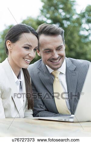 Happy businesspeople using laptop outdoors View Large Photo Image Stock Image - Happy businesspeople using laptop outdoors. Fotosearch