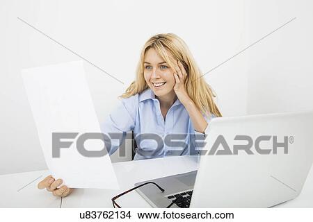 Happy businesswoman reading document in office View Large Photo Image Picture - Happy businesswoman reading document in office. Fotosearch