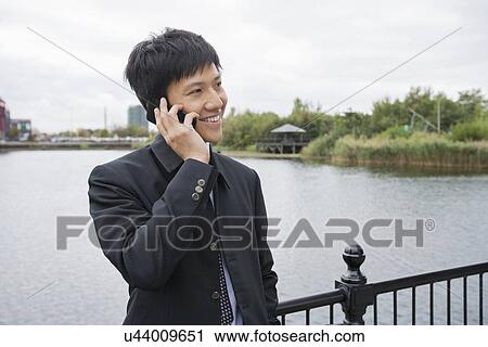 Happy mid adult businessman using cell phone at bridge railing View Large Photo Image Stock Image - Happy mid adult businessman using cell phone at bridge railing. Fotosearch
