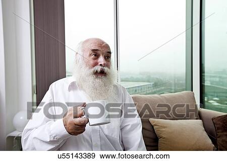 Happy senior man holding coffee cup at home View Large Photo Image Stock Photo - Happy senior man holding coffee cup at home. Fotosearch