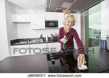 Happy senior woman cleaning kitchen counter View Large Photo Image Stock Image - Happy senior woman cleaning kitchen counter. Fotosearch