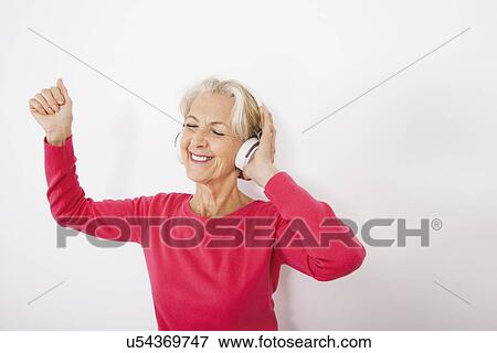 Stock Photo - Happy senior woman listening music over white background. Fotosearch