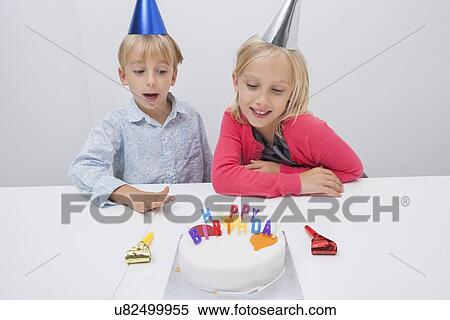 Happy siblings looking at birthday cake on table in house View Large Photo Image Stock Photography - Happy siblings looking at birthday cake on table in house. Fotosearch