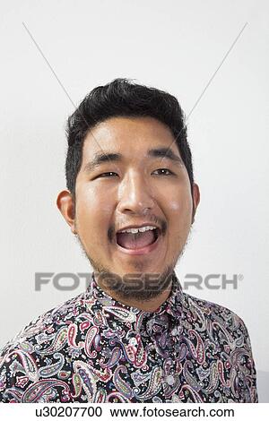 Stock Image - Happy young man looking away against white background. Fotosearch