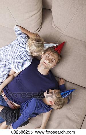 High angle view of father and children with artificial mustache and party hat sleeping on sofa bed View Large Photo Image Stock Photography - High angle view of father and children with artificial mustache and party hat sleeping on sofa bed. Fotosearch